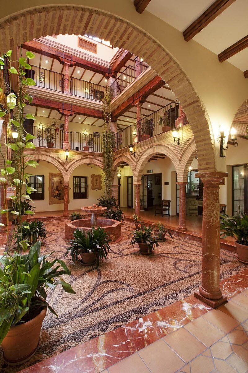 An arched, mosaic-floored cloister looking through to the hotel's planted courtyard
