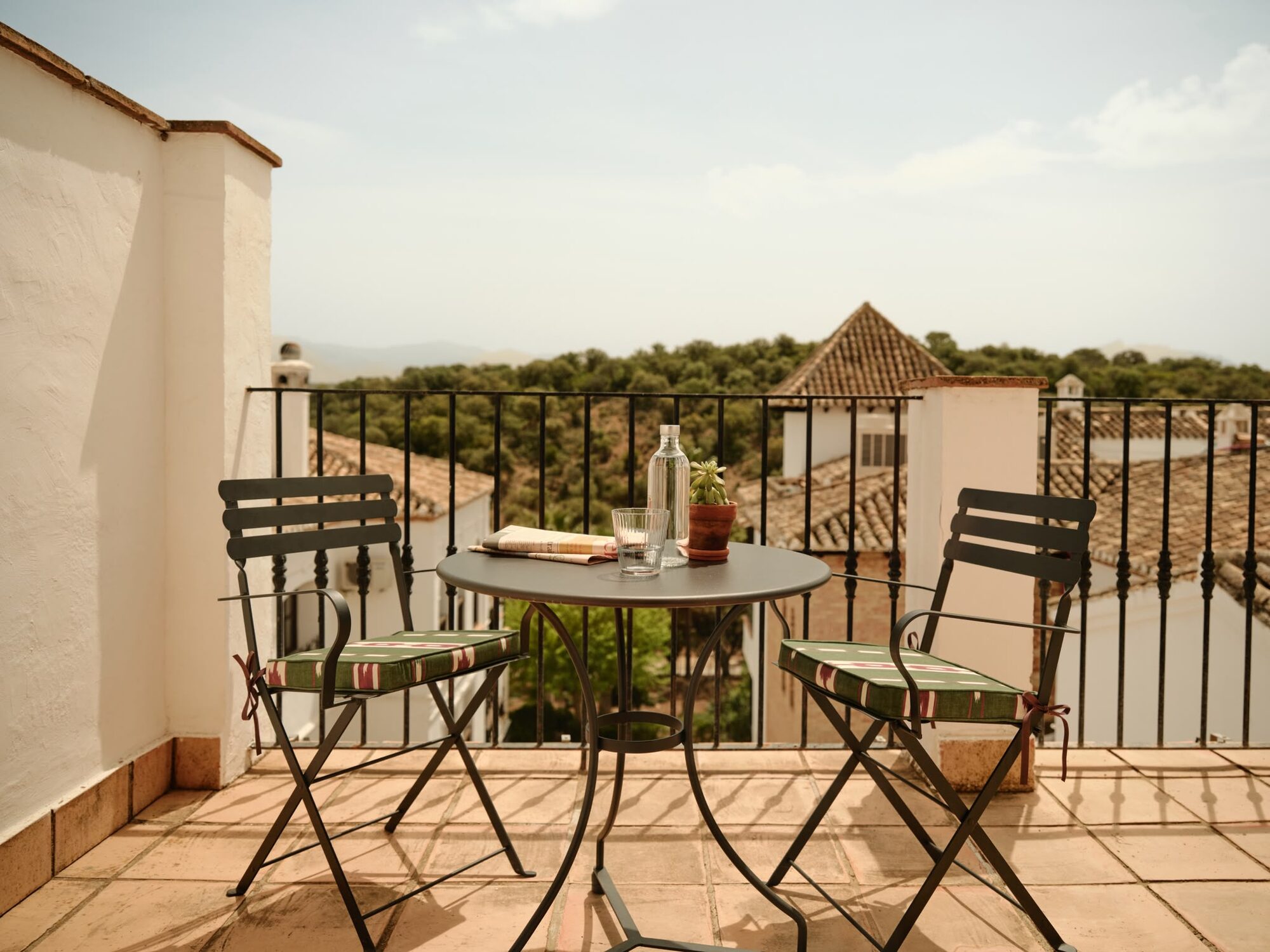 A private terrace with a table set for two, looking over rooftops to the hills beyond